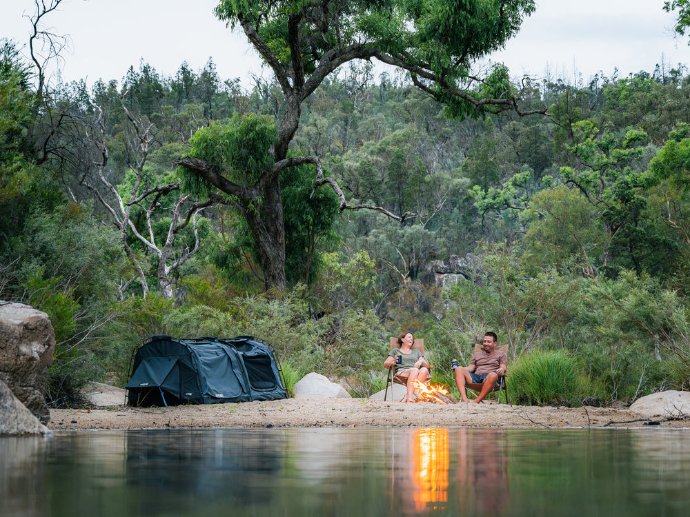 Kakadu Sundowner Swag Tent Folded Out Near The Water With People Relaxing Next To It