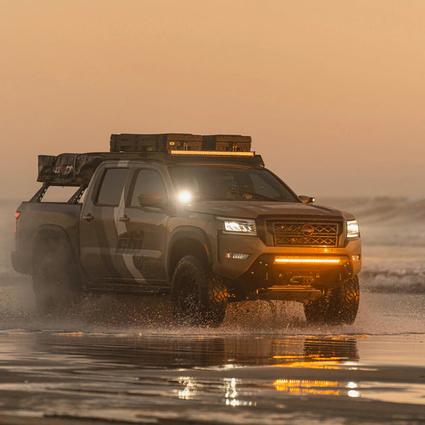 Nissan frontier going trough water with a mounted CBI front bumper that has a running LED light bar