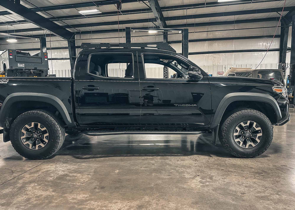 Backwoods Adventure Mods 2005-2023 2nd and 3rd Gen Toyota Tacoma bolt-on Rock Sliders installed on a black Tacoma