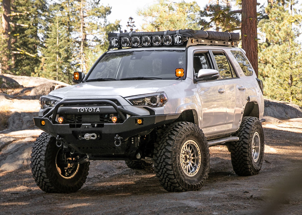 5th Gen Toyota 4runner equipped with a Backwoods Adventure Mods Hi-Lite Overland Front winch Bumper with Prerunner Bull Bar driving off road in the forest