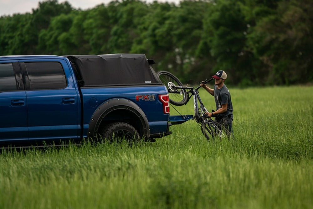 Person Putting Away A Bike Inside The Ford Truck Bed With The Ford Fas-Top Solo Soft Truck Topper Installed 