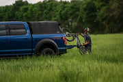 Person Putting Away A Bike Inside The Ford Truck Bed With The Ford Fas-Top Solo Soft Truck Topper Installed 