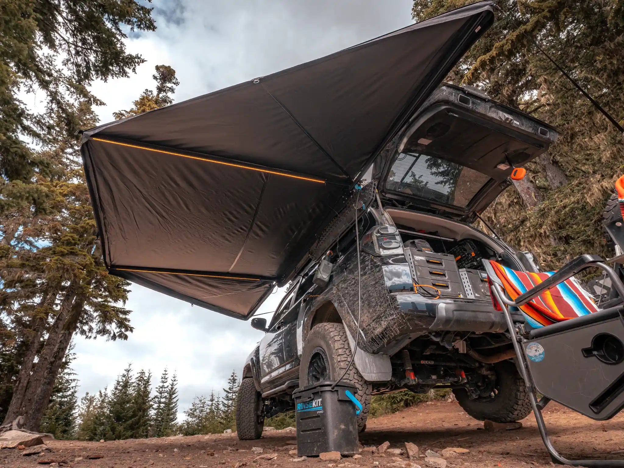 FSR 180 Awning V2 roof rack awning deployed along the side of a vehicle with LED lighting on at camp