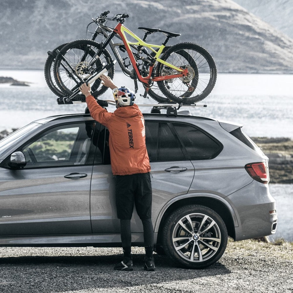 Side View Of A Person Mounting Bikes Onto Thule UpRide Bike Racks