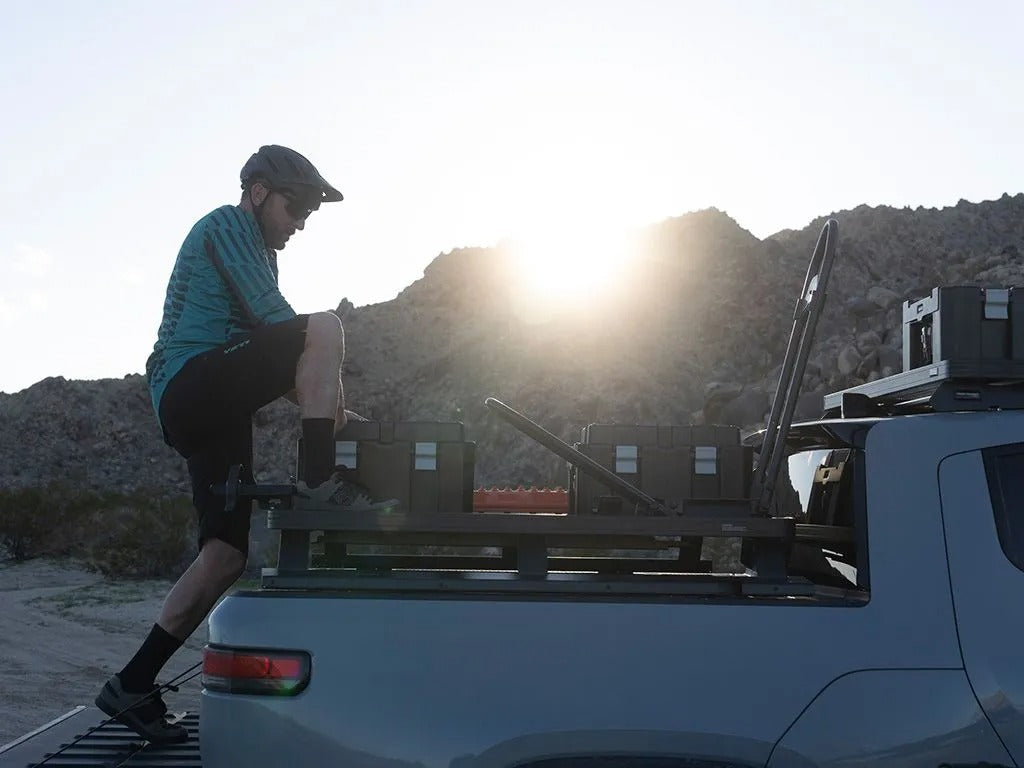 person climbing on a front runner rivian r1t bed rack