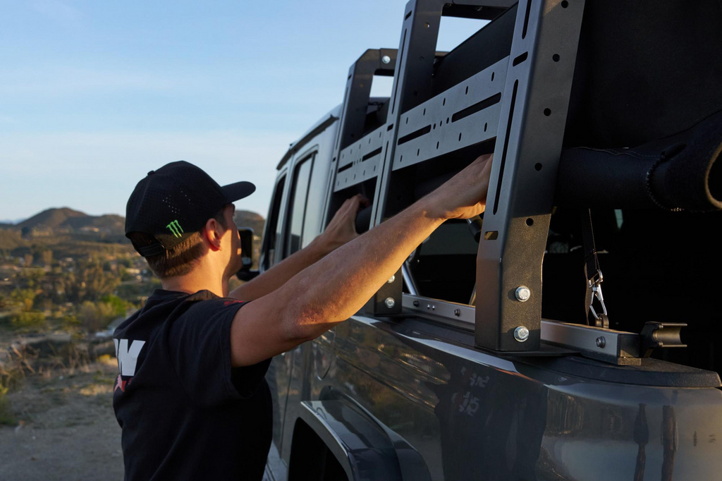 A man rolling down the side of the softopper canopy while having a SofTopper Exo Truck Bed Rack Installed