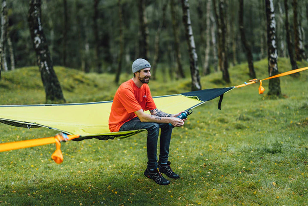 Tentsile Duo 2 person double camping hammock with a person sitting in it between trees
