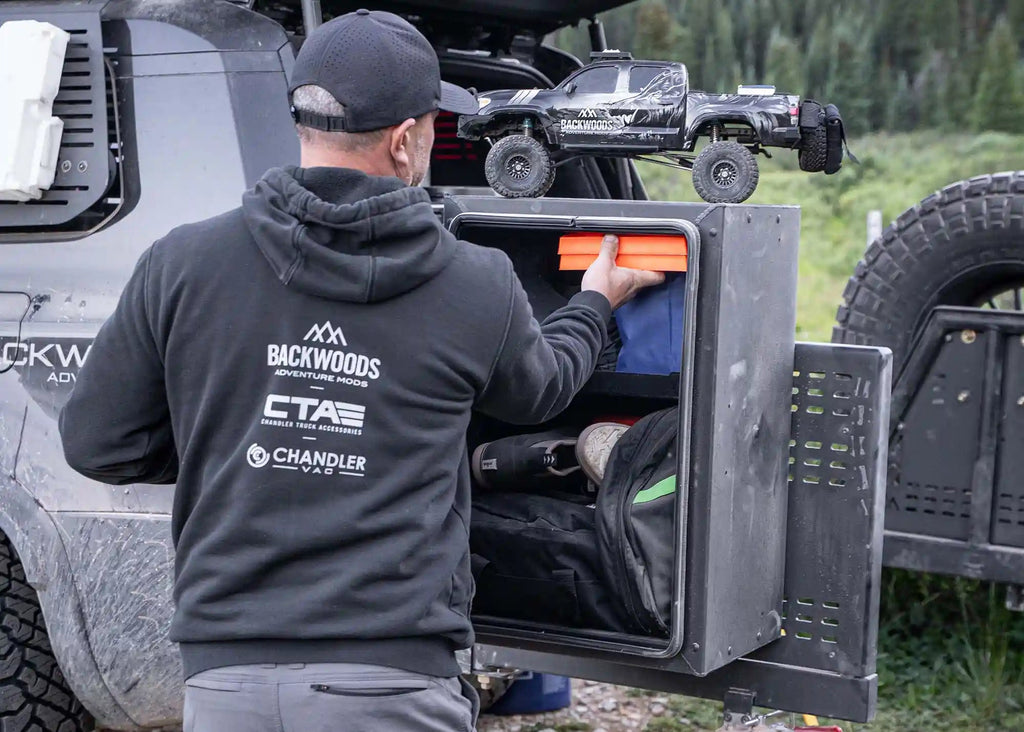 Man removing gear from Backwoods Universal Overland Storage Box while camping