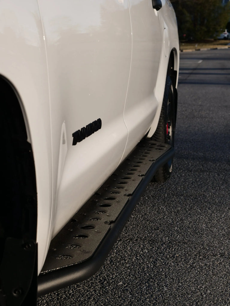 Cali Raised LED Step Edition Rock Sliders Attached On A Toyota With A Filler Plate