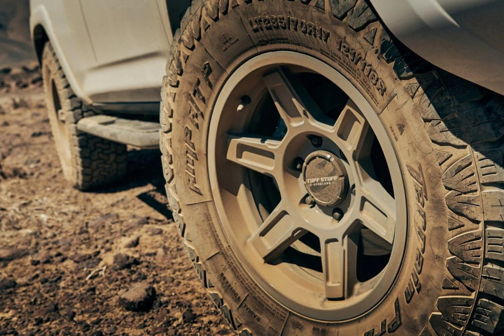 Tuff Stuff Overland Ascend Wheel 17x8.5 Gloss Back Mounted On A Vehicle Driving Through Rocky Terrain
