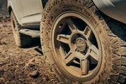 Tuff Stuff Overland Ascend Wheel 17x8.5 Gloss Back Mounted On A Vehicle Driving Through Rocky Terrain