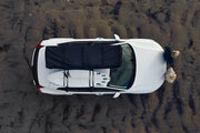 Packed Thule 2-Person Roof Top Tent next To A surf Board On A Vehicles Roof Rack