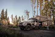 Nissan frontier with a mounted CBI front bumper parked with a deployed roof top tent