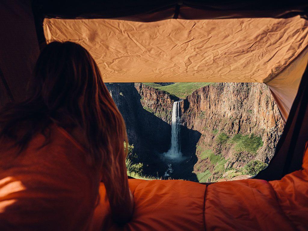 A Camper Looking At A Waterfall Through The The Front Runner Roof Top Tent Entrance